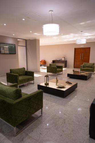 a lobby with green chairs and a table at BOMBONATO HOTEL - Fácil Acesso ao Aeroporto e parque de Exposições ABCZ in Uberaba