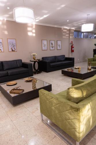 a living room with couches and tables in a room at BOMBONATO HOTEL - Fácil Acesso ao Aeroporto e parque de Exposições ABCZ in Uberaba