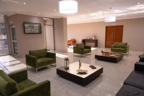 a living room with green chairs and a table at BOMBONATO HOTEL - Fácil Acesso ao Aeroporto e parque de Exposições ABCZ in Uberaba
