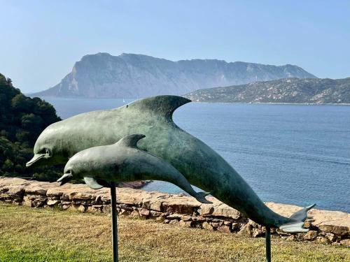 two statues of two birds standing next to the water at Punta Est bellissimo 3 camere vista mare in Capo Coda Cavallo