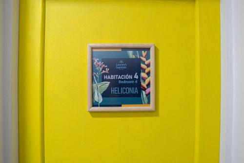 a yellow wall with a picture of a sign on it at Laureles Garden Hostel in Medellín