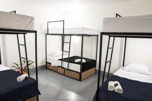 a room with two bunk beds with white sheets at Laureles Garden Hostel in Medellín