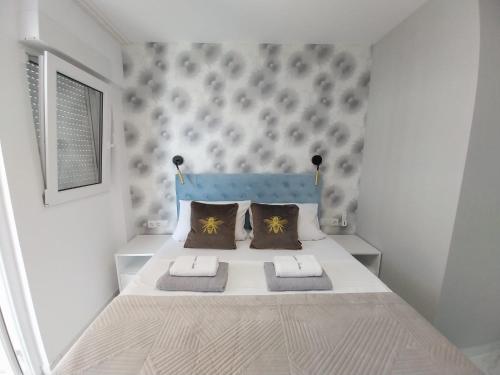 a small white bedroom with a bed with two pillows at Gandia Playa Apartament Claudia Lux con vistas al mar in Playa de Gandia