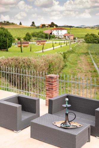 a patio with two chairs and a table and a fence at Notte nella Botte in Vignale Monferrato