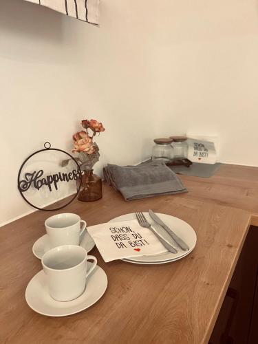 a wooden table with two cups and plates on it at M&N Apartments in Bad Bevensen