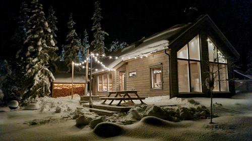 a cabin with a picnic table in the snow at night at Fjellyx i funäs med relax&bastu, badtunna, 13 bädd in Funäsdalen
