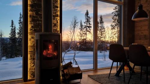 a fireplace in a room with a view of the snow at Fjellyx i funäs med relax&bastu, badtunna, 13 bädd in Funäsdalen