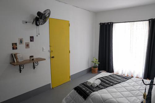 a bedroom with a bed and a yellow door at Laureles Garden Hostel in Medellín