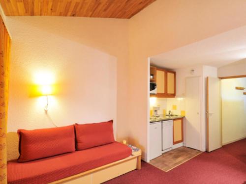 un salon avec un canapé rouge et une cuisine dans l'établissement Résidence Le Carrousel - Studio fonctionnel · Skis aux pieds · Vue vallée · Terrasse MAE-3712, à Les Coches