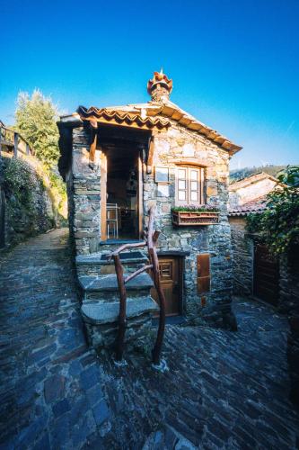 a stone house with a statue in front of it at Montanhas do Xisto - Casa do Portal in Lousã