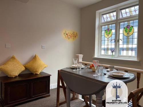 a dining room with a table and stained glass windows at Beautiful Self-contained Cottage in Ickenham