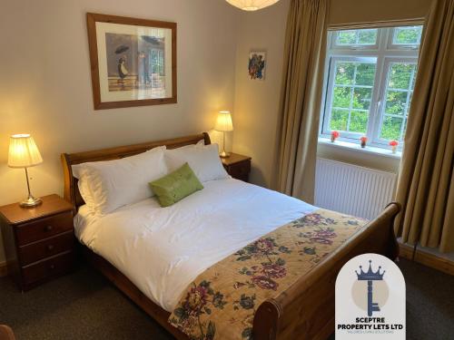 ein Schlafzimmer mit einem Bett und zwei Lampen und einem Fenster in der Unterkunft Beautiful Self-contained Cottage in Ickenham