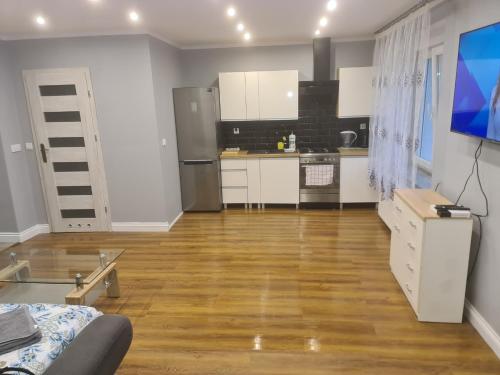 a kitchen with white cabinets and a wooden floor at Apartament mieszkanie do wynajęcia Nicola in Wałbrzych