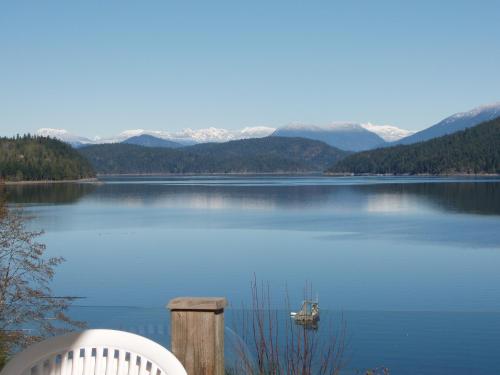 a white chair and a boat on a lake at Shannaghs Sweet Escape in Powell River