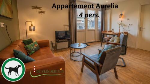 a living room with a couch and chairs and a tv at De Vlindertuin in Nes