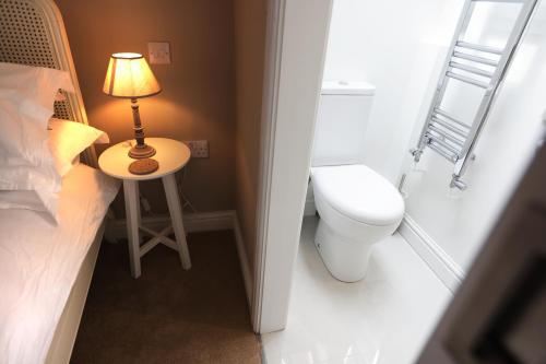 a small bathroom with a toilet and a lamp on a table at The Bakehouse in Chipping Norton