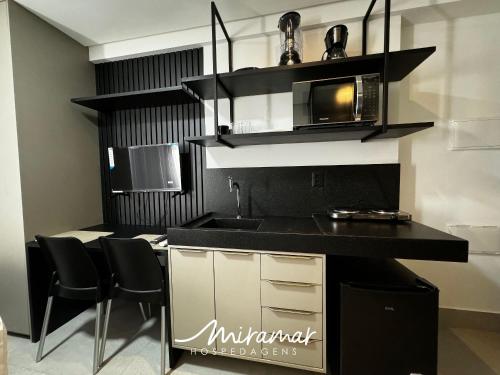 a kitchen with a black counter top and a microwave at Get By Side - Jardim Oceania in Tambaú