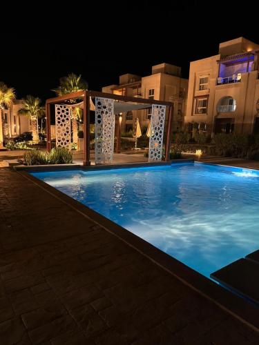 a large blue swimming pool at night at Gaia Luxury chalet in Dawwār Abū Maḩrūs