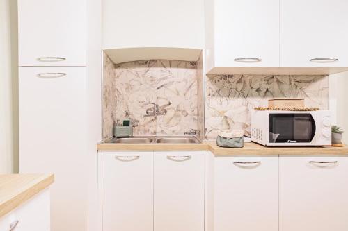 a kitchen with white cabinets and a microwave at Casa Manzoni in Pallanza