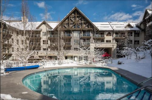 a large apartment building with a swimming pool in the snow at The Aspens by Outpost Whistler in Whistler