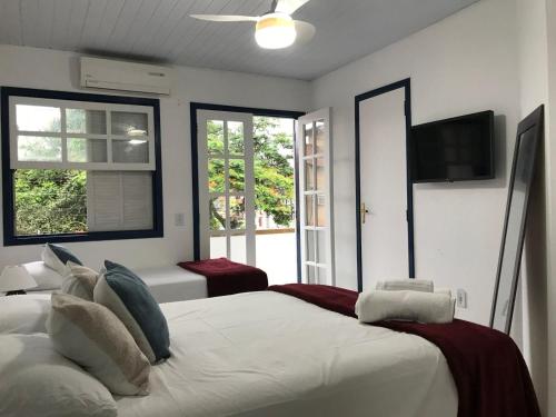 a bedroom with a large white bed and windows at Brothers Suites Centro Búzios in Búzios