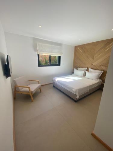 une chambre blanche avec un lit et une chaise dans l'établissement Perla Bianca, à Bonifacio