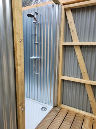 a shower in a corrugatedsteel walled shower with a shower head at Mallard - 5m Luxury Bell Tent at Tregonetha Lake - Tylda Tents in Saint Columb Major