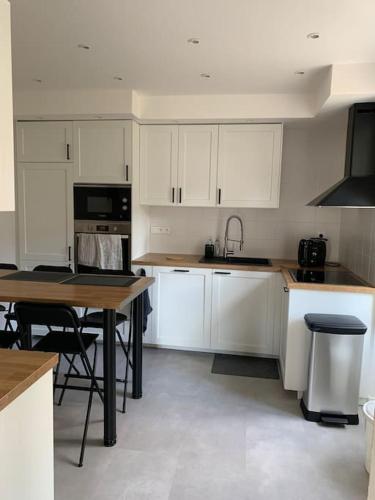 une cuisine avec des armoires blanches et une table en bois dans l'établissement La Maison de Marie, à Biollet