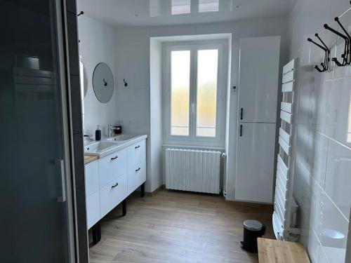 a white bathroom with a sink and a window at La Maison de Marie in Biollet