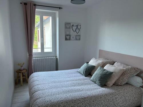 a bedroom with a bed with pillows and a window at La Maison de Marie in Biollet