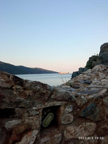 a stone wall with a hole in it next to the water at Hippocampus House in Stratónion