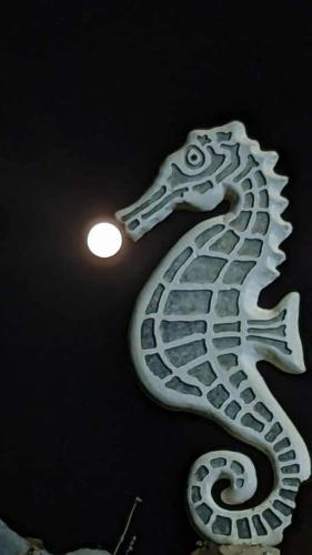 a white seahorse sign hanging on a wall at Hippocampus House in Stratónion