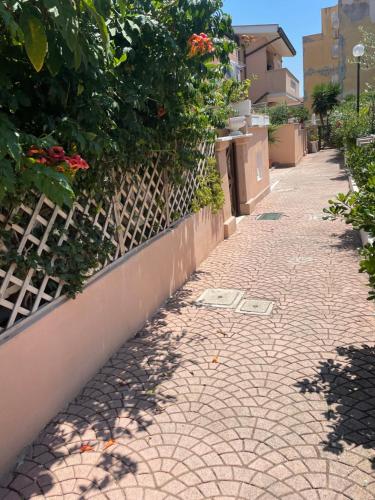 a brick sidewalk next to a fence with flowers at House Turi in Ardea