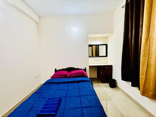 a bedroom with a blue bed with red pillows at AL-KABEER SERENE POND RETREAT KOWDIAR 4bhk in Trivandrum