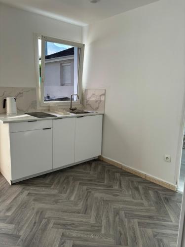 Una cocina blanca con fregadero y espejo. en Maison à Mantes la jolie, en Mantes-la-Jolie