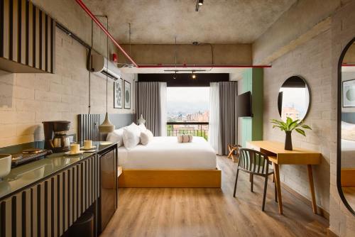 a bedroom with a bed and a kitchen with a table at Urbit Social Lofts in Medellín
