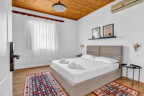 a white bedroom with a white bed and a rug at Nika's Guest House in Berat