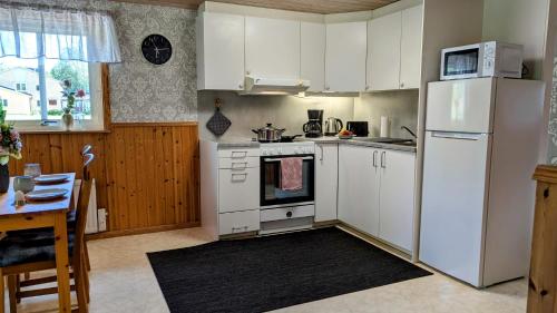 a kitchen with white cabinets and a white refrigerator at Rolig häst, Kaneeling Stugby AB in Dalskog