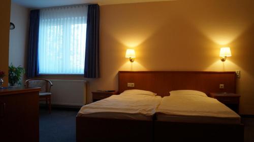 a bedroom with a bed and two lamps on the wall at Landhotel Wilhelm Busch in Lüthorst