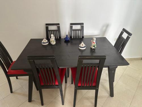 een zwarte eettafel met vier stoelen en beeldjes erop. bij WHY NoT! in Agadir