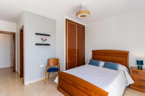 a bedroom with a wooden bed and a chair at Apartamento Paquita R&R in Aguadulce