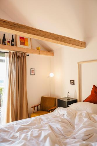 a bedroom with a bed and a chair and a window at MÓD in Lendava
