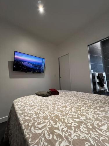une chambre avec un lit avec une télévision à écran plat au mur dans l'établissement Appartement Neuf Côté La Défense, à Courbevoie