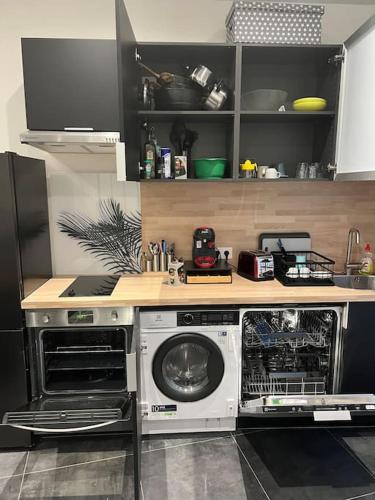 une cuisine avec un lave-linge et un sèche-linge sous un comptoir dans l'établissement Appartement Neuf Côté La Défense, à Courbevoie
