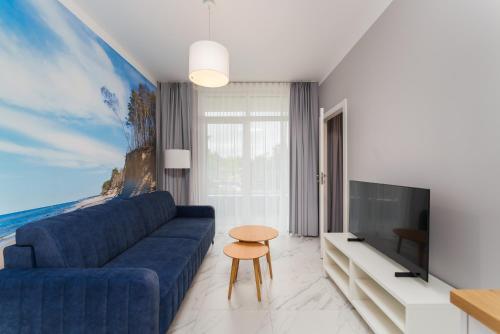 Una sala de estar con un sofá azul y un televisor. en Apartament Baltic Park IIIB z Basenem Letnim by HolidaySun, en Sianożęty