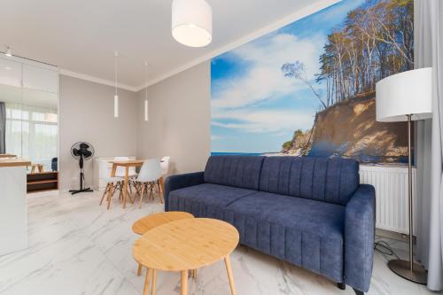 Una sala de estar con un sofá azul y una mesa. en Apartament Baltic Park IIIB z Basenem Letnim by HolidaySun, en Sianożęty