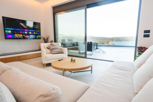 a living room with white furniture and a large window at Panoramic Villa in Tolo