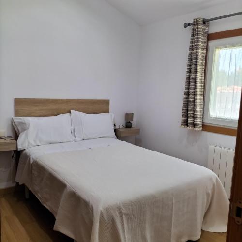 a bedroom with a bed with white sheets and a window at A casa do castaño in Nigrán