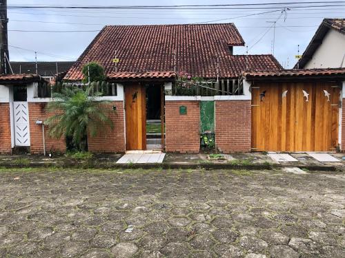 a brick house with wooden doors and a courtyard at Casa Grande com 3 suítes in Peruíbe