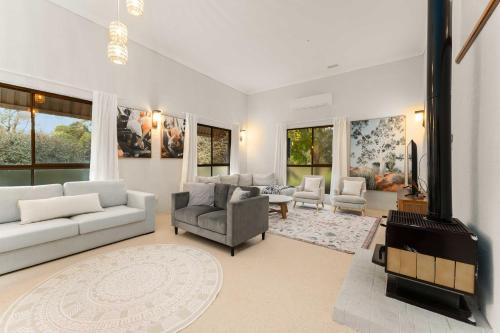 a living room with white furniture and a fireplace at The Bower at Purling Brook in Springbrook